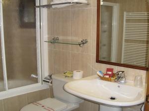 a bathroom with a toilet and a sink and a mirror at Villa Russell Hotel&Apartments in Torla-Ordesa
