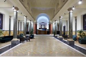 a lobby with columns and chairs and a large hall at Hotel The Building in Rome