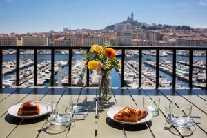 ein Tisch mit zwei Tellern Essen und Blick auf einen Hafen in der Unterkunft Superbe Appartement, vue Notre Dame de la Garde, Vieux port in Marseille