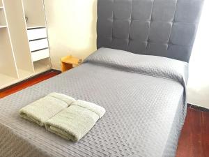 a bed with a gray headboard with a towel on it at Departamento Primer Piso - Embajada USA in Lima