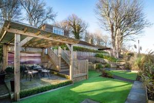 a backyard with a wooden pergola and green grass at Beach Approach House - 30 steps from beach - Luxury house - kids slide and chill-out room - amazing location - garden in Filey