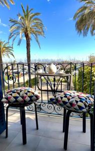 a balcony with two chairs and a table and palm trees at Entire Flat First Beach line - Sea Views - Vilanova i Geltru in Vilanova i la Geltrú