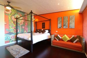 a bedroom with an orange wall with a bed and a couch at Mystery13 in Luodong