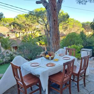 a table with a white table cloth and chairs and a tree at Villa Pina 100 meters from the sea in Fort Village
