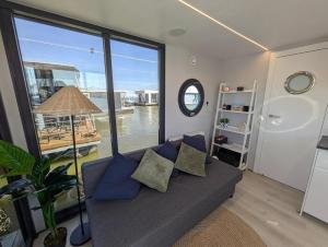 a living room with a couch and a large window at Gezellige houseboat Eclipse Monnickendam nabij Amsterdam in Monnickendam