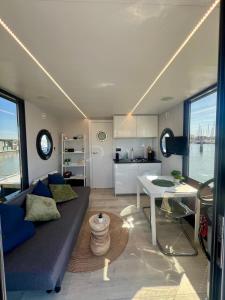a living room with a couch and a table at Gezellige houseboat Eclipse Monnickendam nabij Amsterdam in Monnickendam +5 photos