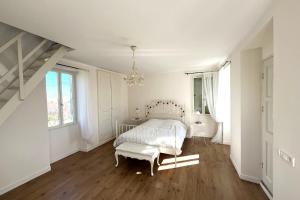 a white bedroom with a bed and a chandelier at L’Atelier du Valet - Vigoux in Vigoux