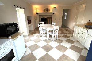a kitchen with a table and chairs on a checkered floor at L’Atelier du Valet - Vigoux in Vigoux