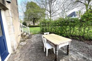 a wooden table and a chair sitting outside of a house at L’Atelier du Valet - Vigoux in Vigoux