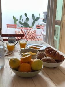 Una mesa con dos platos de pan y un bol de fruta. en Casa Dar Alma, en Vila Real de Santo António