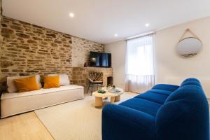 Una sala de estar con muebles azules y una pared de ladrillo. en L'Evasion Bretonne - Superbe T3 - Centre Ville - Balnéo, en Quimper