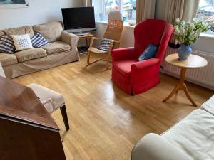 a living room with a red chair and a couch at Anchor Cottage in Seaview