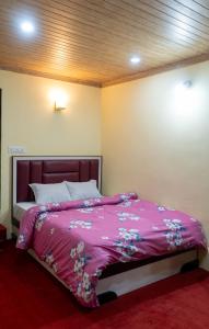 ein Schlafzimmer mit einem großen Bett mit einer rosa Decke in der Unterkunft Gangamaya Homestay Darjeeling in Darjeeling