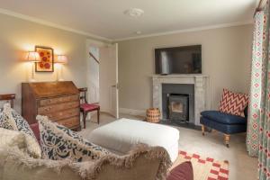 a living room with a fireplace and a tv at Laundry Cottage in High Legh