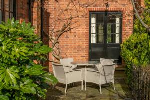 a patio with a table and chairs in front of a brick building at Laundry Cottage in High Legh