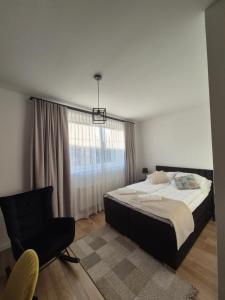 a bedroom with a bed and a chair and a window at Pokoje pod Kamienną Bramą in Chojnice