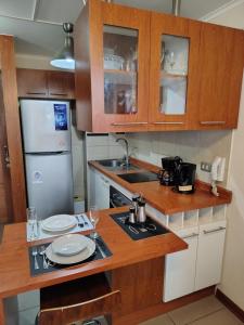Una cocina con gabinetes de madera y un refrigerador blanco. en DSalas 445 con estacionamiento Concepcion, en Concepción