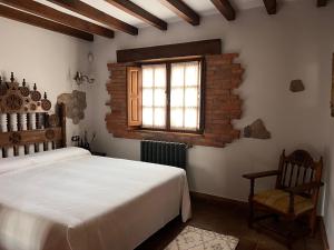 a bedroom with a bed and a window and a chair at Apartamentos Villa Julieta in Ruente