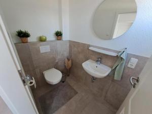 a bathroom with a sink and a toilet and a mirror at Wangermeerglück in Wangerland