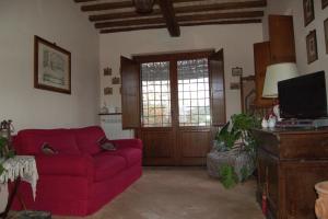 a living room with a red couch and a tv at Casale La Quercia in Pian D'artino