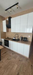 una cucina con mobili bianchi e un lavandino di Apartament Bursztynowa Laguna a Ustronie Morskie Altre 13 foto