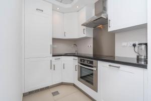 Una cocina blanca con gabinetes blancos y un fregadero. en SmartConceptLiving Studio with Burj Khalifa View in Downtown Dubai, en Dubái 5 fotos más