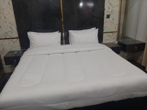 a large bed with white sheets and pillows at Radiant Gust House in Islamabad