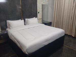 a large bed with white sheets and pillows in a room at Radiant Gust House in Islamabad