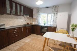 a kitchen with wooden cabinets and a white table at Spacious apartment Near National Arena, parks in Bucharest +12 photos
