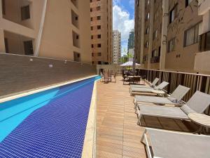 a swimming pool with chaise lounge chairs next to buildings at Via Brisa Apartment in Brasília