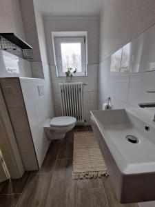 ein Badezimmer mit Waschbecken und Toilette und einem Fenster in der Unterkunft Wohnung Goldblick in Teschendorf