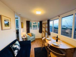 a living room with a table and chairs and a window at The Rural Woodside Cabin by MaisonPro in Stroud