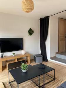 a living room with a coffee table and a flat screen tv at La Risloise in Pont-Audemer