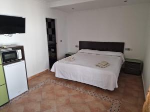 a bedroom with a white bed and a flat screen tv at Habitaciones y Estudios Miramar in Bolonia