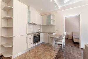 a kitchen with white cabinets and a table and chairs at Modern Flat near City Center with Parking, Smart TV & Wi-Fi in Rīga