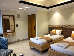a hotel room with two beds and a chair at Hotel Centro Residential in Chittagong