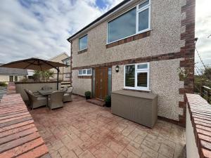 a patio with a table and chairs and an umbrella at Math Holiday Cottage in Pentraeth