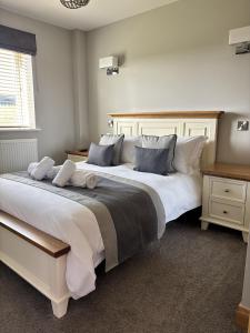 a bedroom with a large white bed with pillows at Math Holiday Cottage in Pentraeth