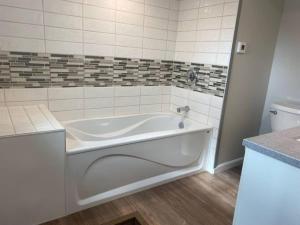 a white bath tub in a bathroom with a toilet at Bay Street Blue Ludington Park in Escanaba +85 photos