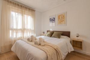 a white bedroom with a large bed with towels on it at El Retiro de Julián in Santa Pola
