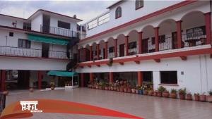 a large white building with balconies and a courtyard at Hotel Del carmen in Santa Catarina Juquila