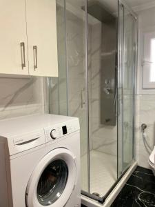 a washing machine in a bathroom with a shower at Luxury beach apartment in Néa Péramos