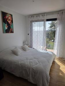 a white bedroom with a large bed and a window at La P'tite Créole in Auzon