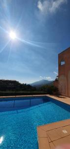 a large swimming pool with the sun in the sky at Architect's studio with pool, sea view and AC in Théoule-sur-Mer