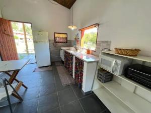 a kitchen with a counter and a refrigerator and a table at Chalé Vila do Lago 2 - 5min do Centro de Joa in Joanópolis