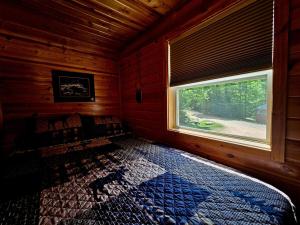 a bedroom with a bed in a wooden cabin with a window at Tiny House Cabin-Presque Isle Campground #30 in Presque Isle