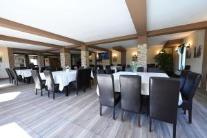 a dining room with white tables and black chairs at Pensiunea Bergtal in Râşnov +29 photos
