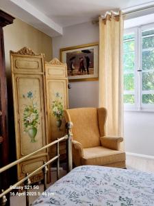 a bedroom with a bed and a chair and a window at Maison Maisy in Navarrenx