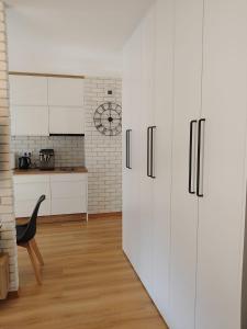 a kitchen with white cabinets and a refrigerator at Apartament dla Dwojga - Apartament typu studio in Dziwnówek