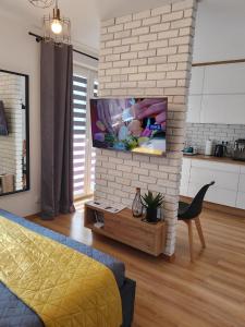 a living room with a tv on a brick wall at Apartament dla Dwojga - Apartament typu studio in Dziwnówek